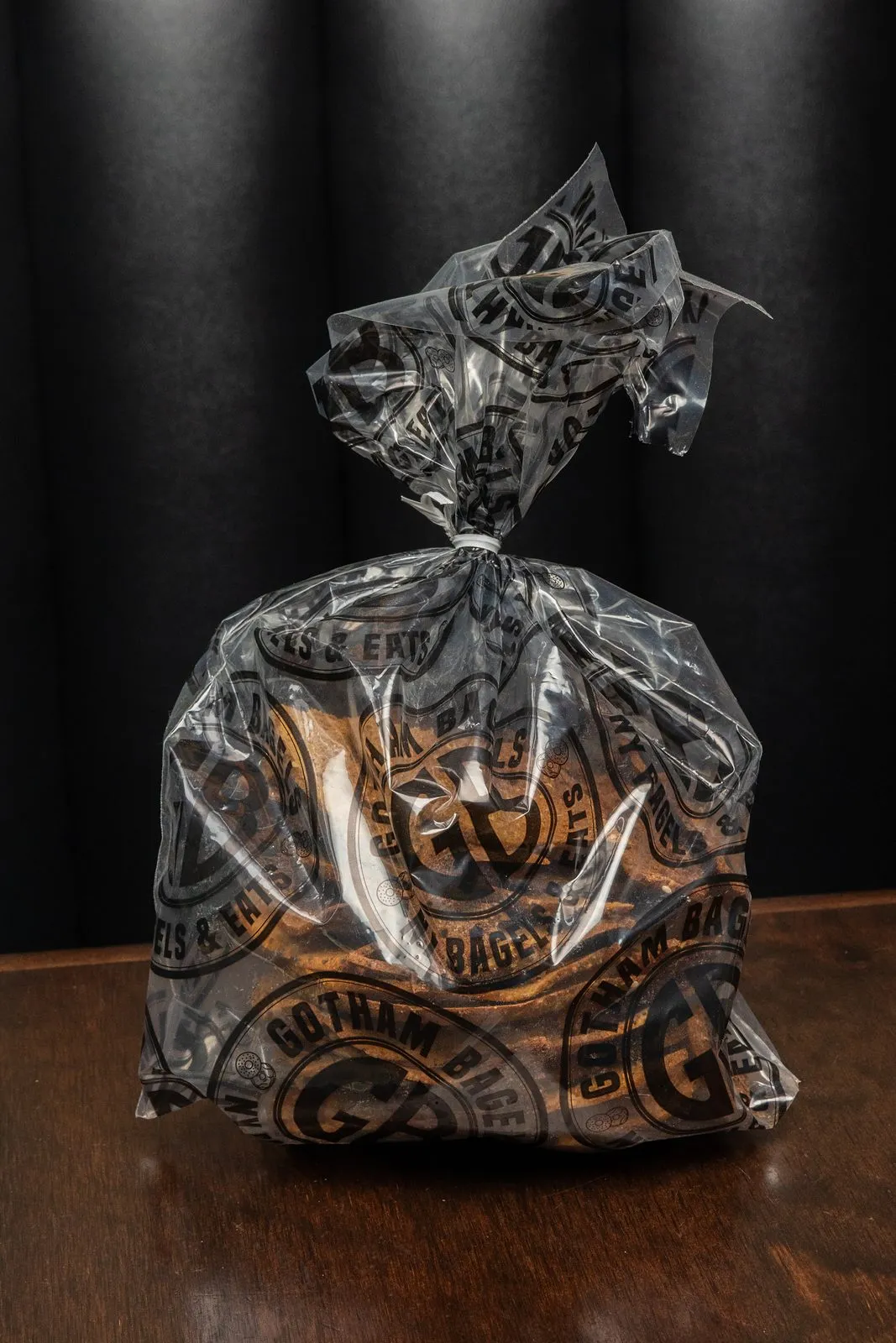 A dozen hand-rolled bagels in a clear Gotham Bagels branded bag
