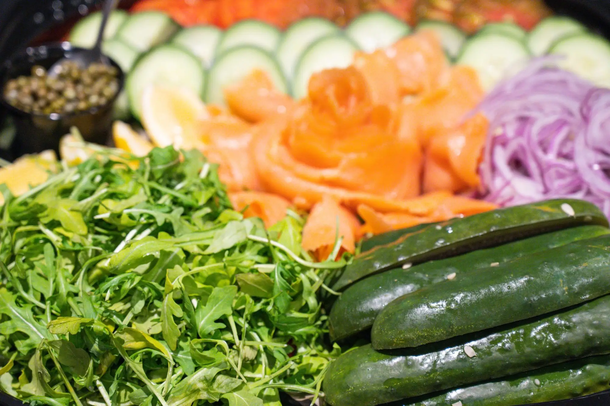 Gotham lox platter: cold-smoked salmon folded into a rose beside arugula, cucumber, red onion, lemon and capers